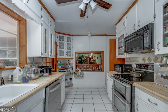 kitchen with white cabinets, light tile patterned floors, stainless steel appliances, ornamental molding, and sink