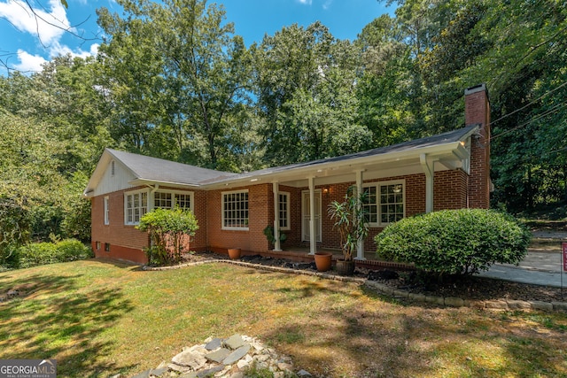 ranch-style home featuring covered porch and a front yard