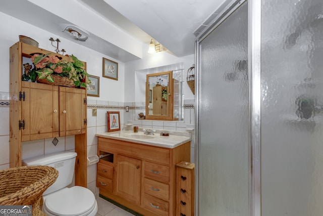 bathroom featuring vanity, tile patterned flooring, a shower with shower door, tile walls, and toilet