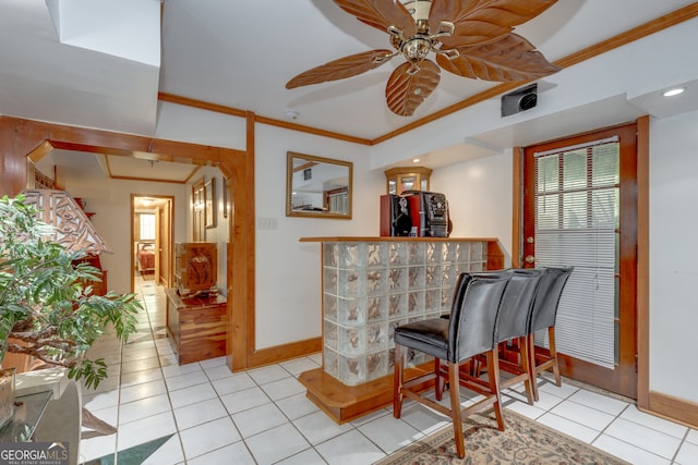 bar featuring ornamental molding, ceiling fan, black refrigerator, and light tile patterned floors