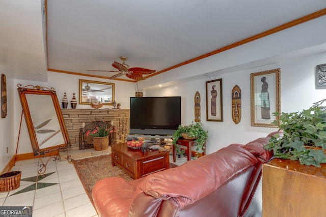 living room with ornamental molding, a stone fireplace, light tile patterned flooring, and ceiling fan