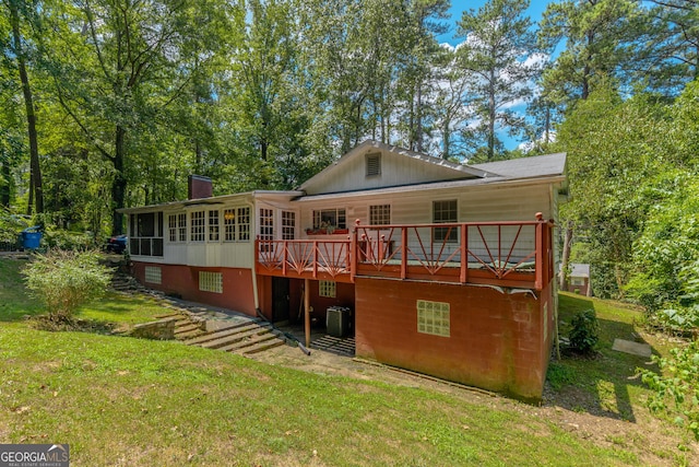 rear view of house featuring a lawn, a wooden deck, a sunroom, and cooling unit