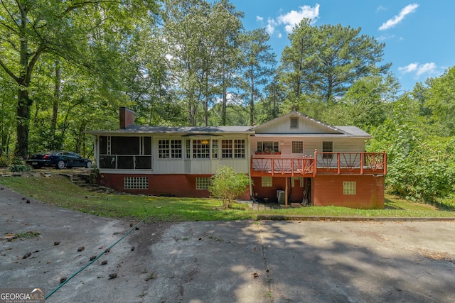 back of house with a deck, a lawn, and a sunroom