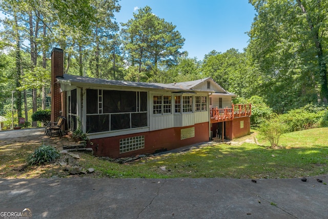 exterior space featuring a front yard, a deck, and a sunroom