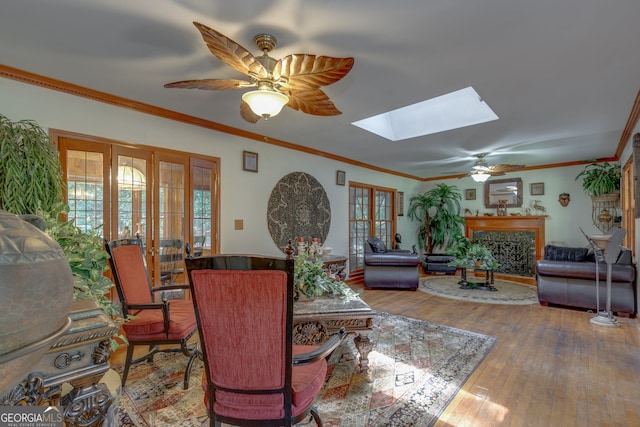 living room with hardwood / wood-style flooring, crown molding, ceiling fan, a skylight, and french doors