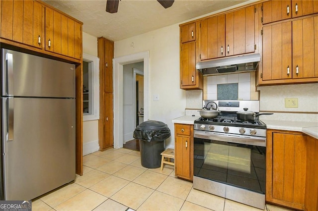 kitchen featuring decorative backsplash, ceiling fan, light tile patterned floors, and stainless steel appliances