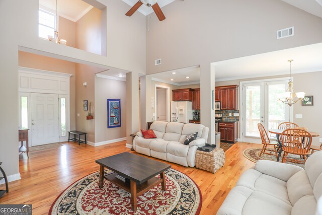 living room featuring light hardwood / wood-style floors, high vaulted ceiling, and ceiling fan with notable chandelier