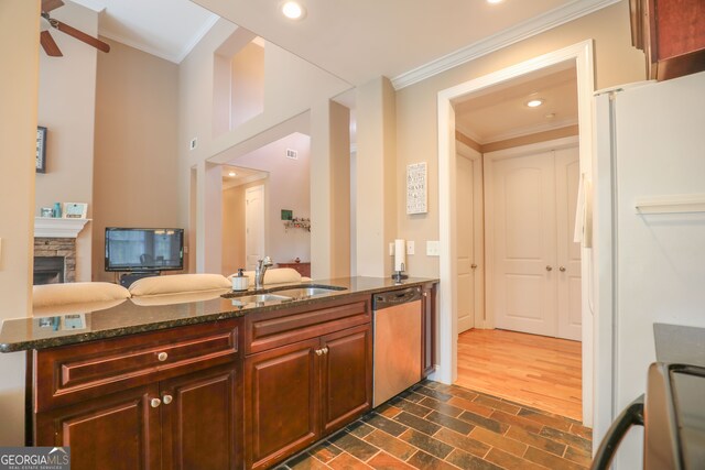 kitchen featuring sink, kitchen peninsula, stainless steel dishwasher, dark stone countertops, and white refrigerator