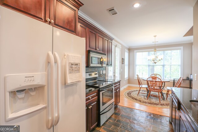 kitchen featuring dark wood-type flooring, stainless steel appliances, crown molding, a notable chandelier, and decorative light fixtures