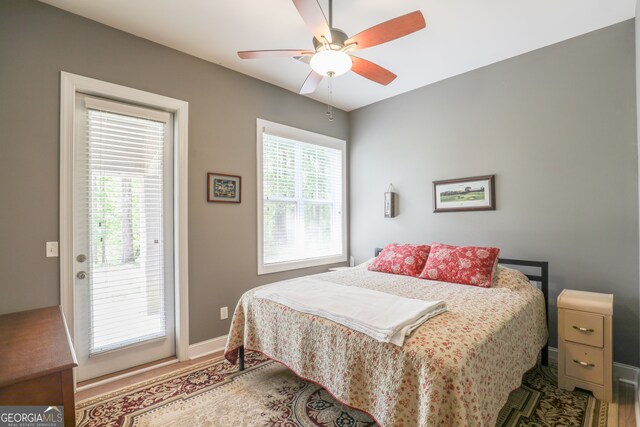 bedroom featuring multiple windows, access to exterior, hardwood / wood-style flooring, and ceiling fan