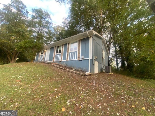 view of home's exterior with a lawn and central AC