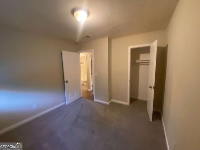 unfurnished bedroom with dark carpet and a closet