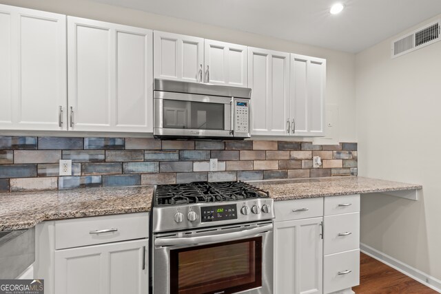 kitchen featuring light stone countertops, white cabinets, backsplash, and appliances with stainless steel finishes