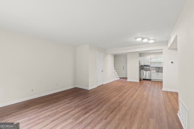 unfurnished living room featuring sink and light hardwood / wood-style floors