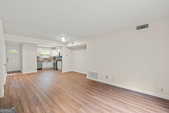 unfurnished living room featuring light hardwood / wood-style floors and sink