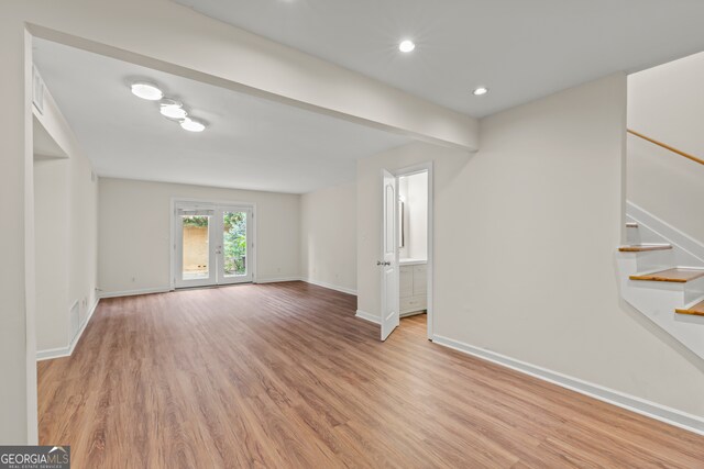 unfurnished living room with light wood-type flooring and french doors