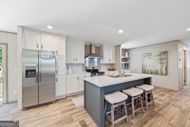 kitchen featuring appliances with stainless steel finishes, white cabinetry, and wall chimney range hood