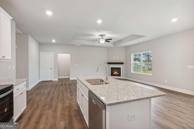 kitchen with dishwasher, a kitchen island with sink, sink, and white cabinetry