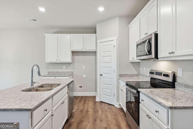 kitchen with wood-type flooring, white cabinetry, appliances with stainless steel finishes, and sink