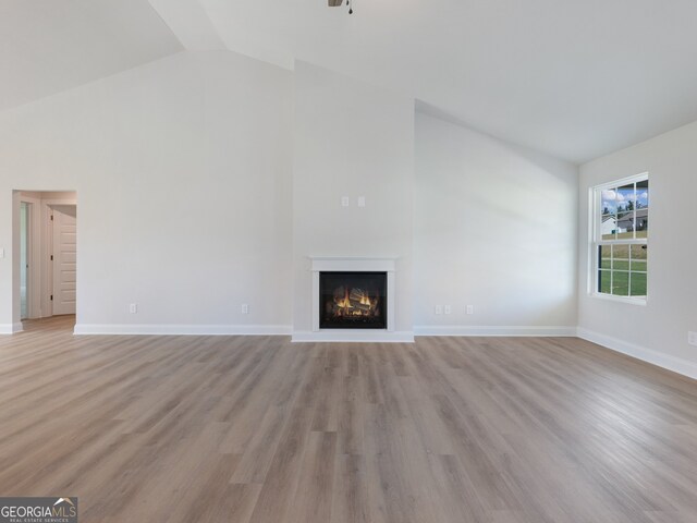 unfurnished living room with vaulted ceiling and light wood-type flooring