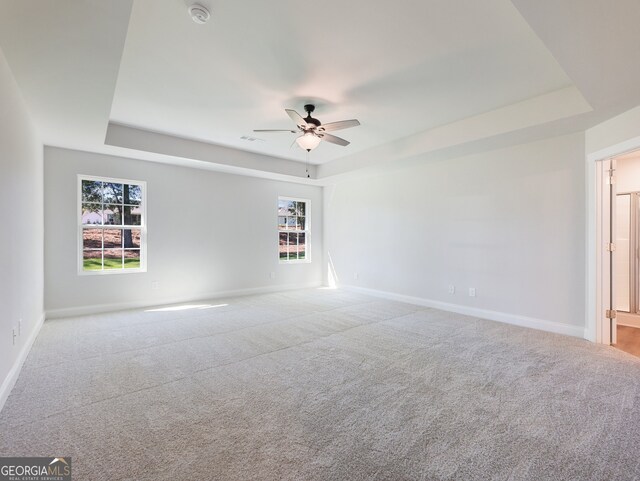 carpeted empty room featuring a tray ceiling and ceiling fan