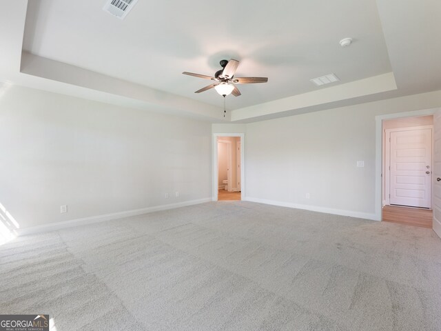 carpeted empty room featuring a raised ceiling and ceiling fan