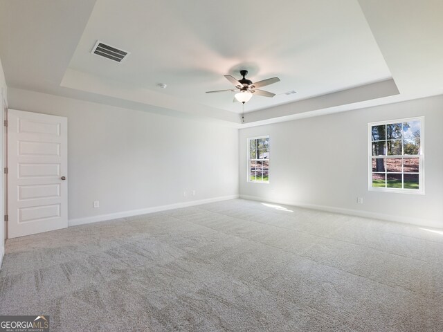 spare room featuring ceiling fan, a raised ceiling, and carpet floors