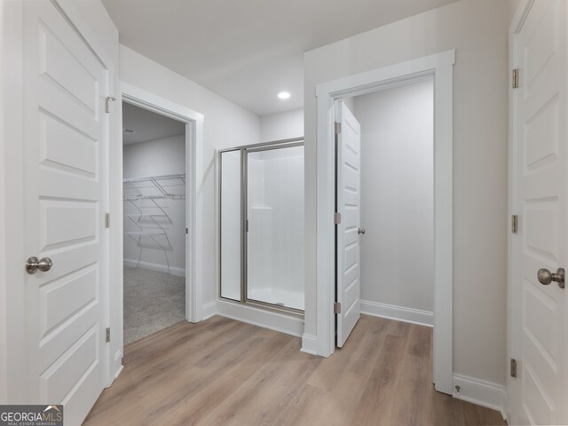 bathroom with hardwood / wood-style flooring and an enclosed shower