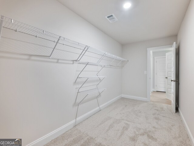 walk in closet featuring light carpet