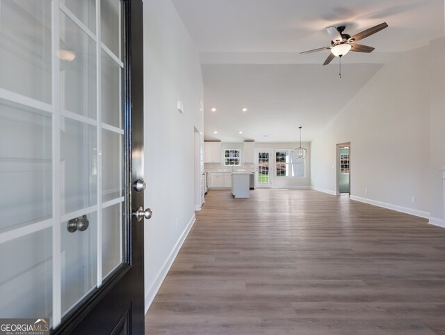 unfurnished living room featuring ceiling fan, wood-type flooring, and vaulted ceiling