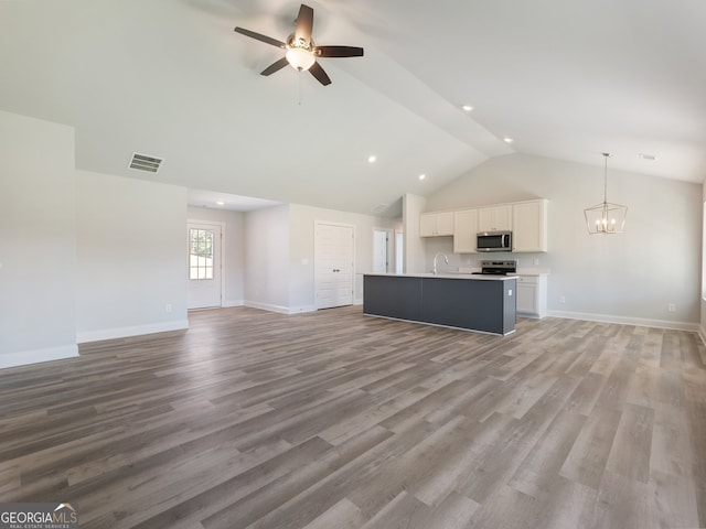 unfurnished living room with ceiling fan with notable chandelier, light wood-type flooring, lofted ceiling, and sink