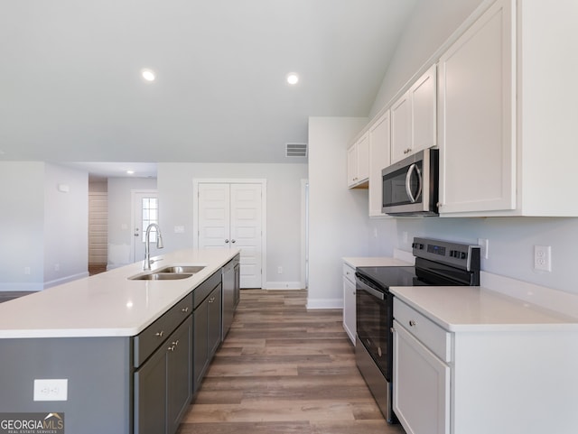 kitchen featuring white cabinets, sink, light wood-type flooring, an island with sink, and appliances with stainless steel finishes