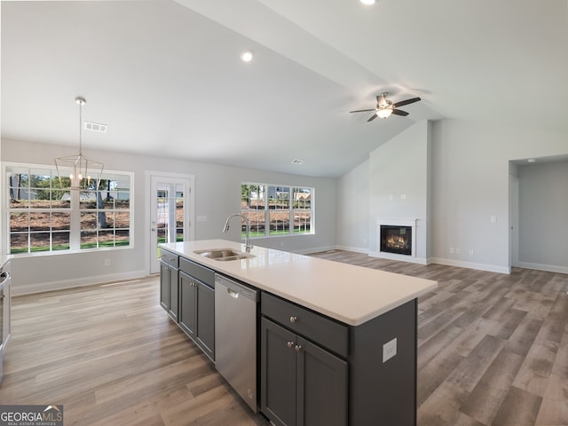 kitchen with dishwasher, sink, light hardwood / wood-style flooring, vaulted ceiling, and a center island with sink