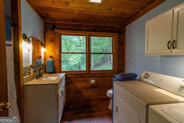 washroom featuring separate washer and dryer, wooden ceiling, dark hardwood / wood-style floors, wooden walls, and sink