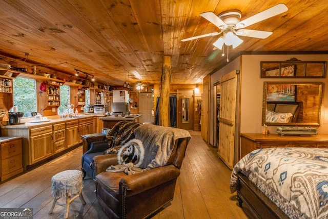 bedroom with wood walls, light hardwood / wood-style floors, wooden ceiling, and sink