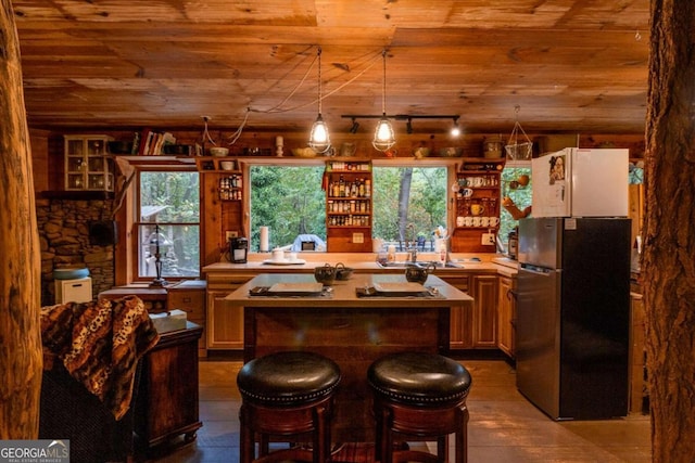 kitchen featuring wood ceiling, wood-type flooring, a kitchen island, stainless steel refrigerator, and a kitchen breakfast bar