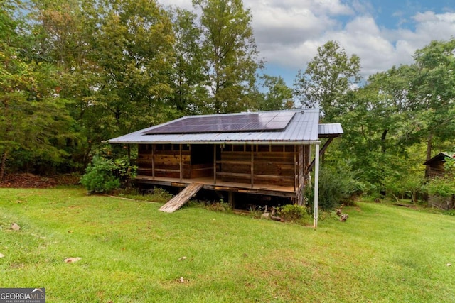 back of house with solar panels and a yard