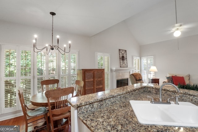 kitchen with ceiling fan with notable chandelier, light stone countertops, sink, and dark hardwood / wood-style floors