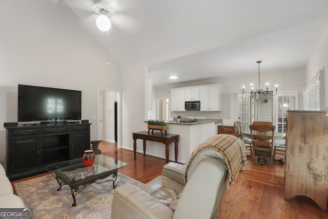 living room with ceiling fan with notable chandelier, hardwood / wood-style flooring, and lofted ceiling