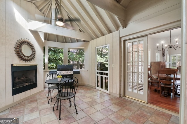 sunroom / solarium featuring vaulted ceiling with beams, a tile fireplace, and a chandelier