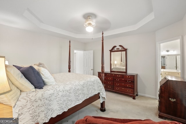 bedroom featuring light carpet, ceiling fan, connected bathroom, and a raised ceiling