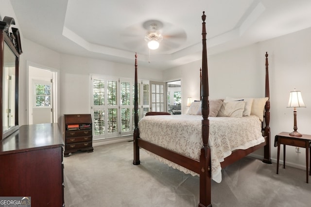 carpeted bedroom with ceiling fan and a raised ceiling