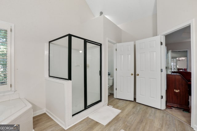 bathroom featuring lofted ceiling, plus walk in shower, wood-type flooring, and toilet