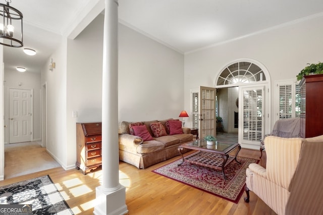 living room with ornate columns, crown molding, hardwood / wood-style floors, and a high ceiling