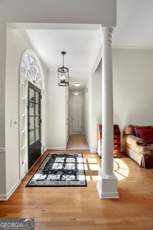 entrance foyer featuring decorative columns, a notable chandelier, crown molding, and wood-type flooring