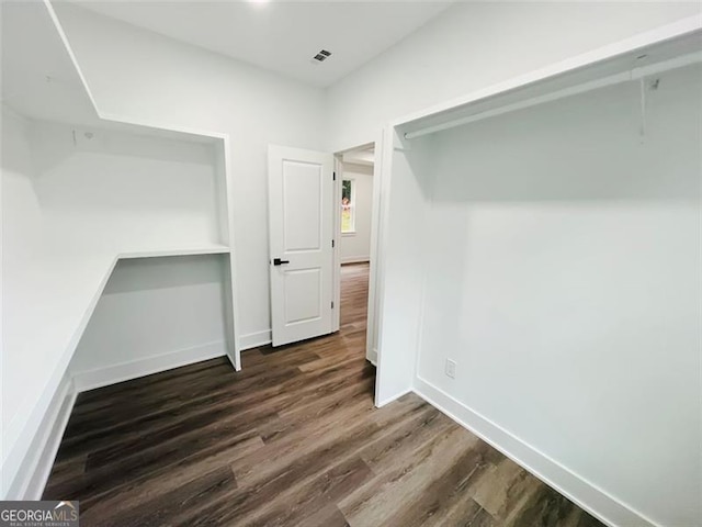 unfurnished bedroom with dark wood-style flooring, visible vents, and baseboards