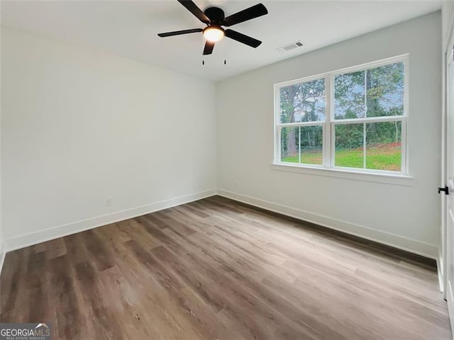 spare room with baseboards, visible vents, and wood finished floors