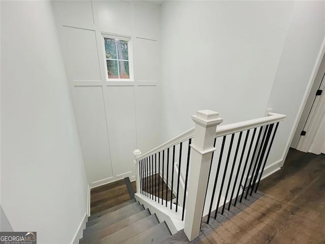 stairs featuring a decorative wall and wood finished floors