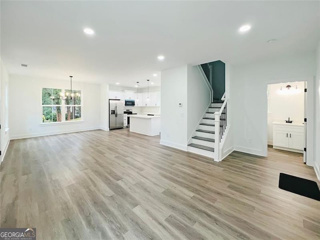 unfurnished living room with a notable chandelier and light wood-type flooring