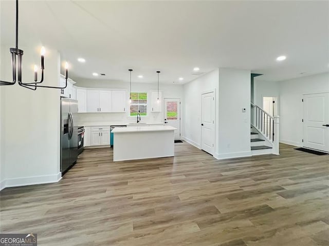 kitchen featuring a center island, stainless steel appliances, light countertops, white cabinetry, and pendant lighting